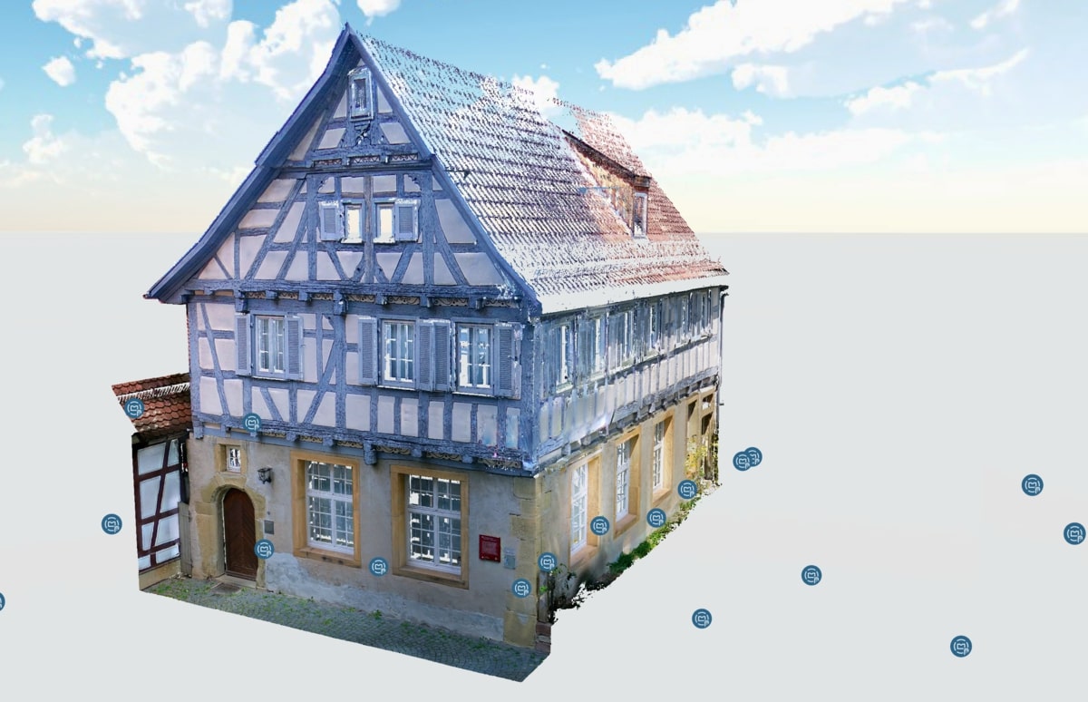 Ein altes Fachwerkhaus mit blauen Balken und Giebeldach vor blauem Himmel.