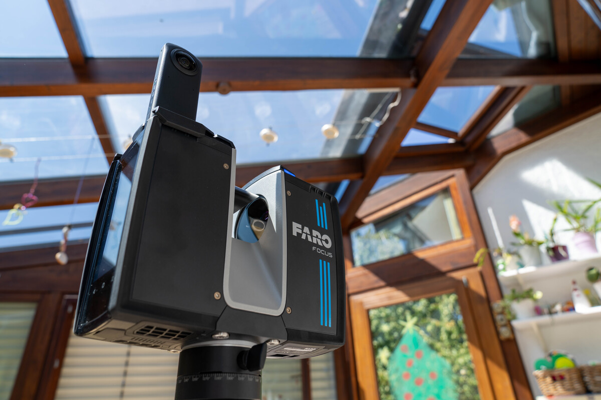 Ein moderner 3D-Laserscanner in einem hellen Raum mit Glasfenster.