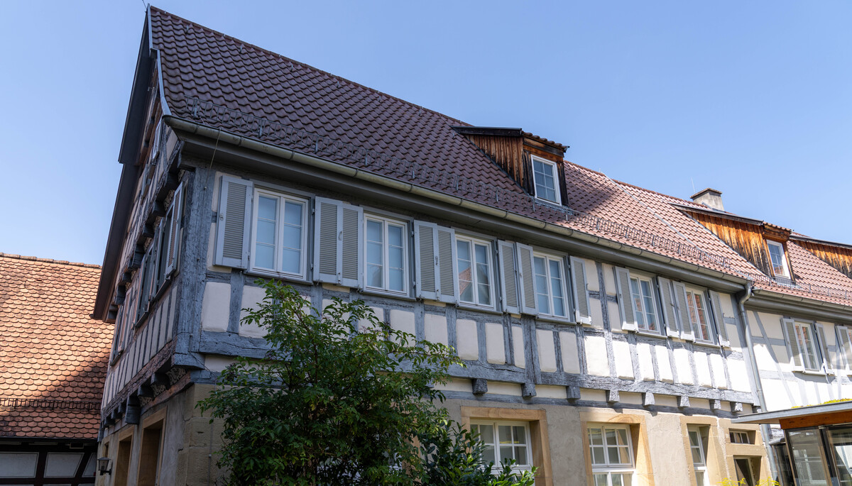 Fachwerkhaus mit weiß-grauer Fassade, roten Dachziegeln und blauer Himmel.